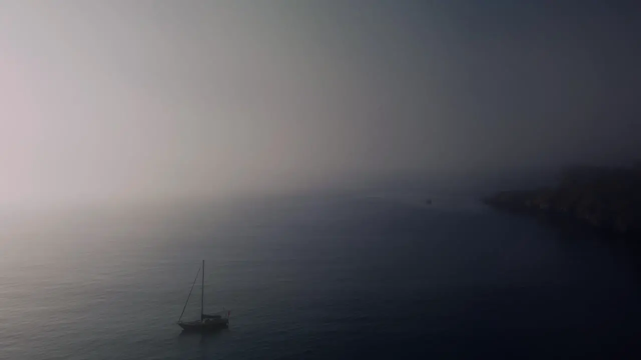 Sailboat anchored off the coast in the fog