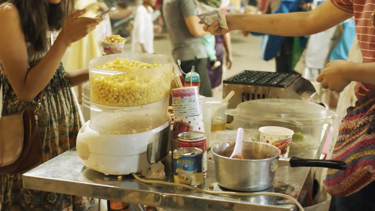 Lady Buying Some Corn at a Snack Stand at Night