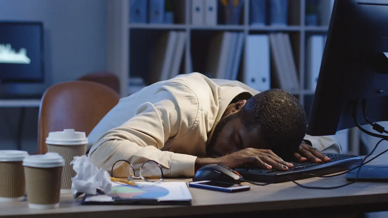 Office Worker Sleeping On The Table In Front Of The Computer In The Office At Night