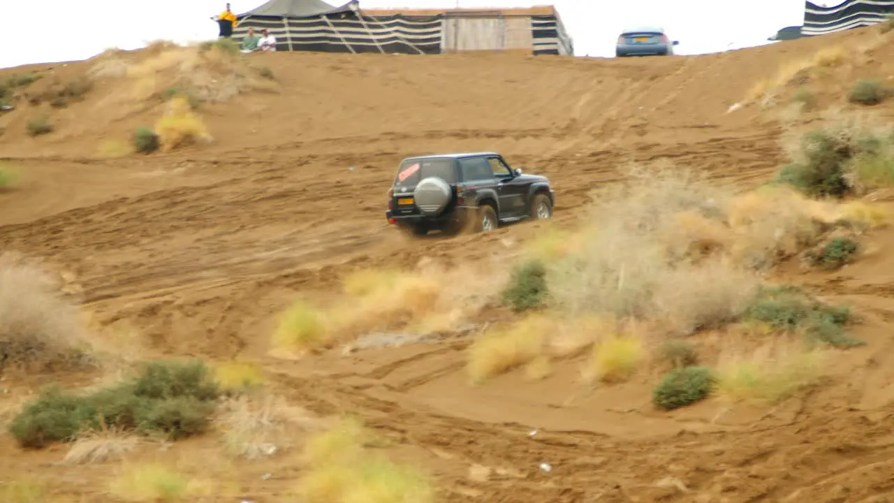 Video of a car racing up a steep hill in the sand dunes showcasing the car's speed and agility as it navigates the challenging terrain