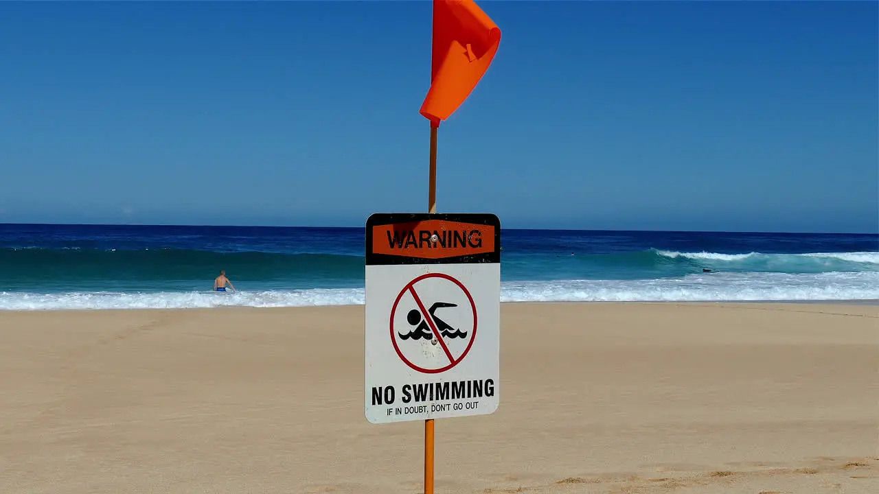 footage of a Warning No swimming sign posted at a beach on the North shore of Oahu Hawaii