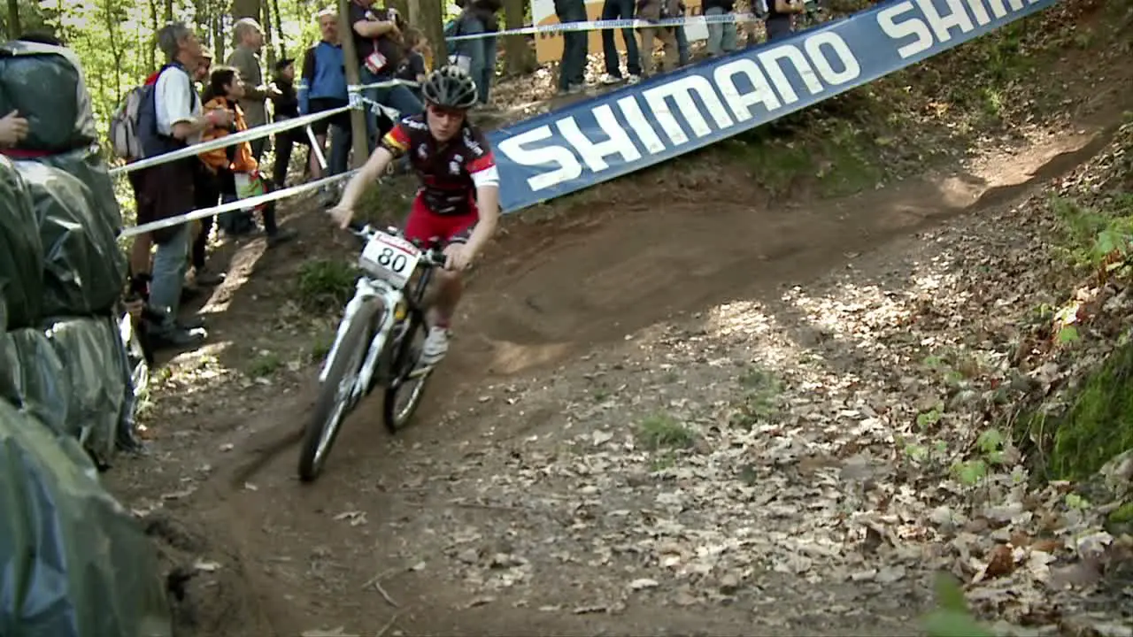 Bicyclists race in the woods as spectators watch