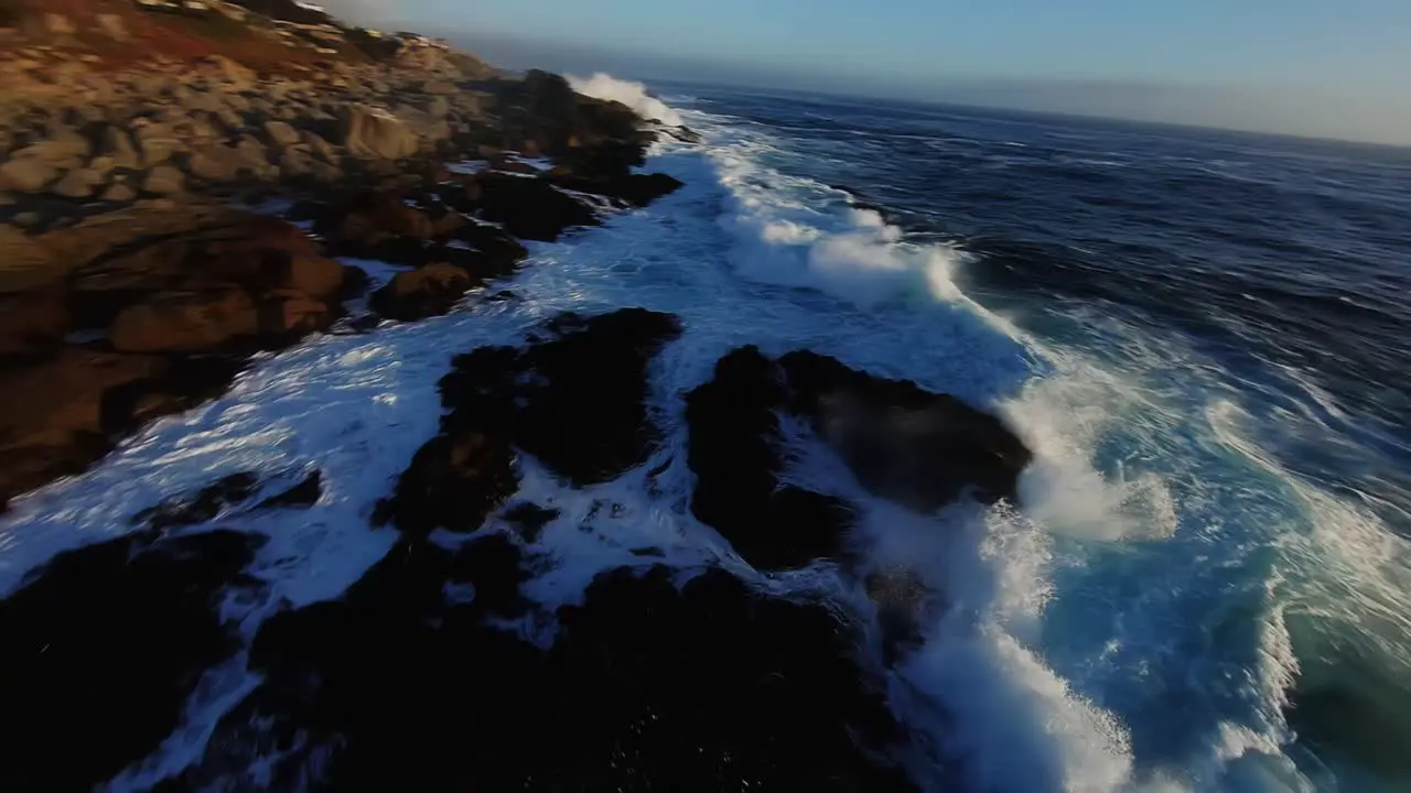 Big waves splashing on rocky coast in rough sea close up FPV aerial view