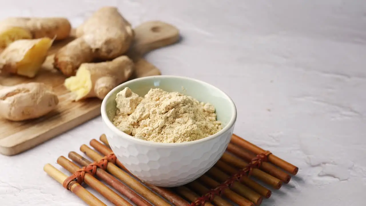 Ginger powder and slice of ginger on table