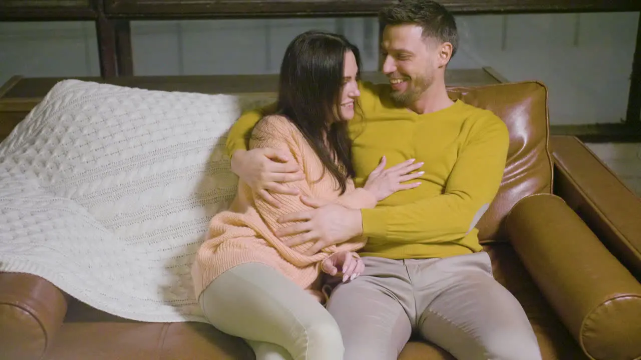 Top View Of A Couple Hugging And Laughing Sitting On Sofa In The Living Room At Home