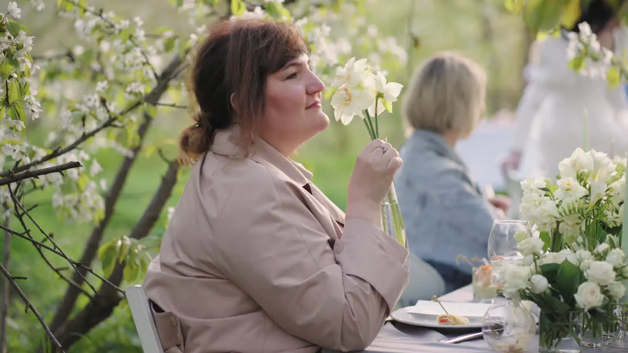 wedding party in garden in spring day female guest is admiring flower decoration