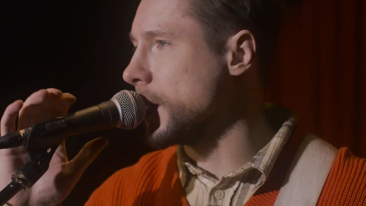 Close Up Of Male Musician Talking Into Microphone Before Live Music Perfomance