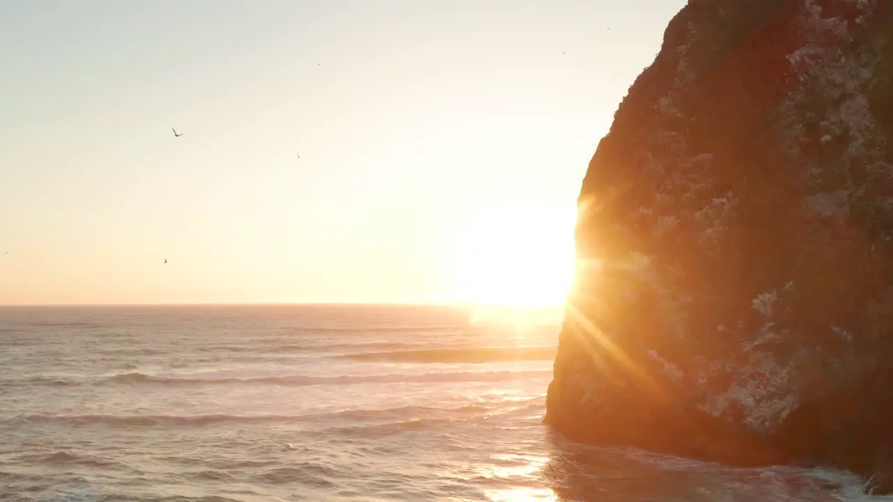 Aerial slider shot past large sea cliffs revealing the sunset