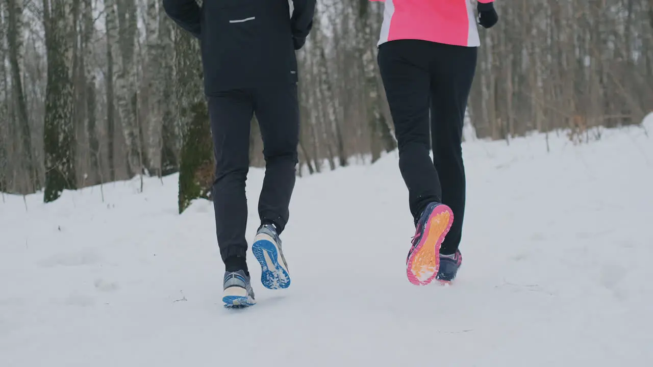 Close-up of the feet of two runners in sneakers running in the winter in the park The married couple goes in for sports