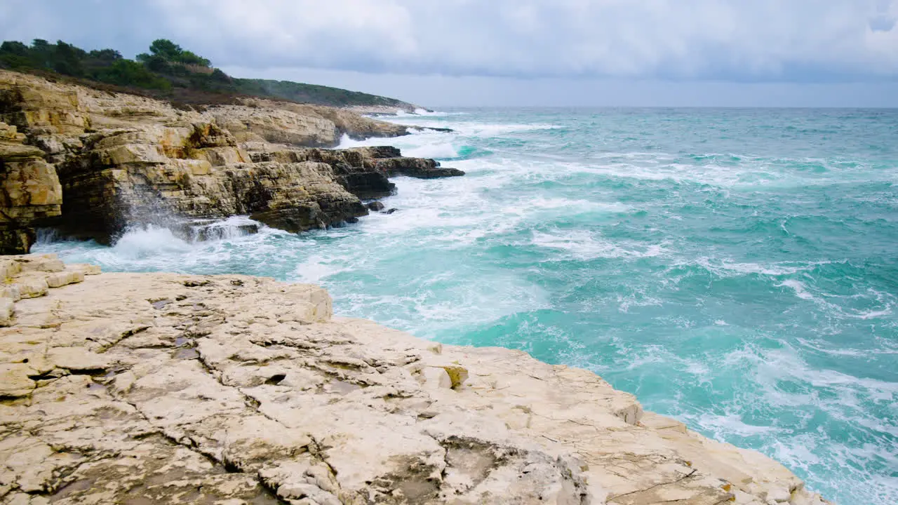 Sea waves breaking on rocky coast forming foam panoramic movement