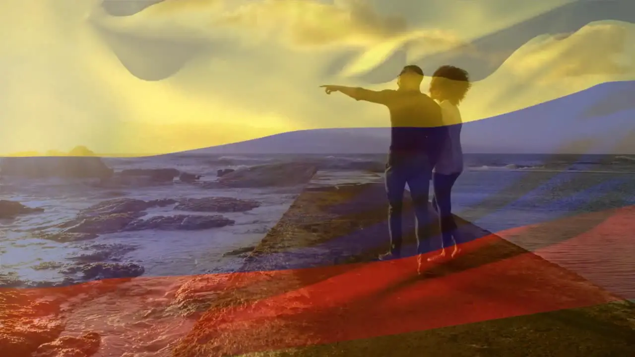 Animation of flag of colombia over african american couple at beach