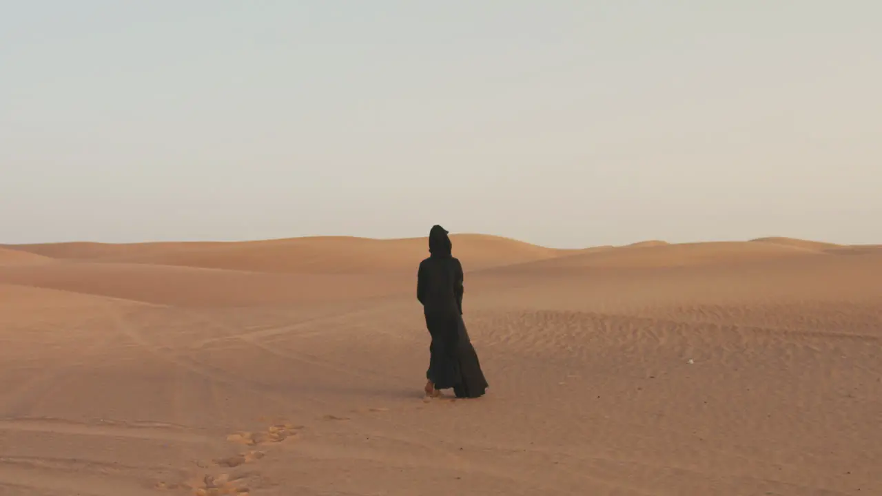 Back View Of A Muslim Woman With Hijab Walking Barefoot In The Desert