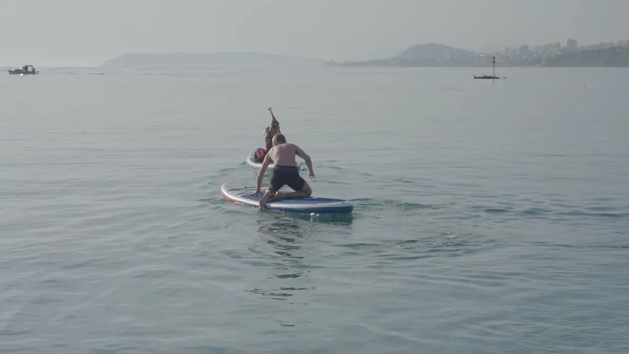 A girl and a man are rowing along a beautiful beach