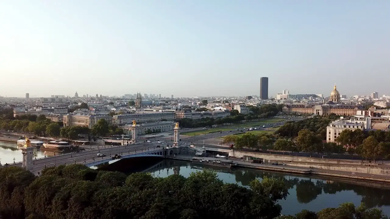 Drone tour of Hotel des invalides at distance from Grand palais over senine river at sunrise featuring Pont Alexandre III with montparnasse tower in the background