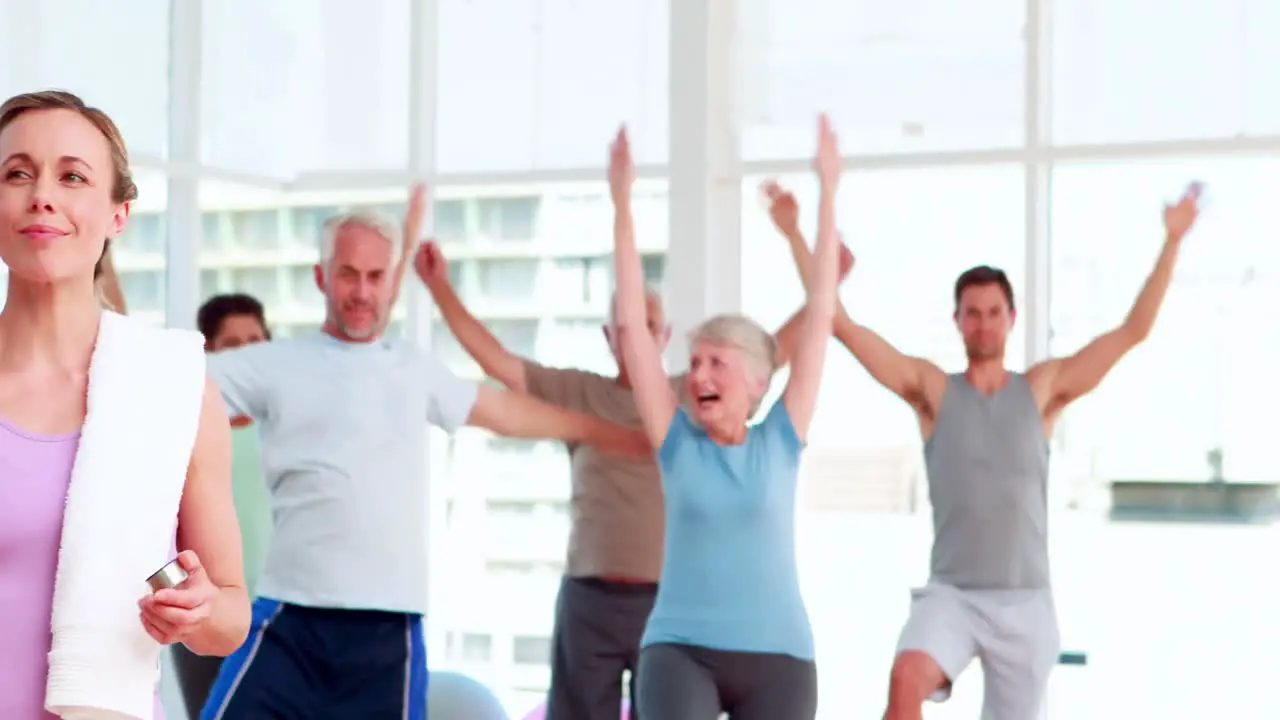 Pilates instructor smiling at camera in front of her class