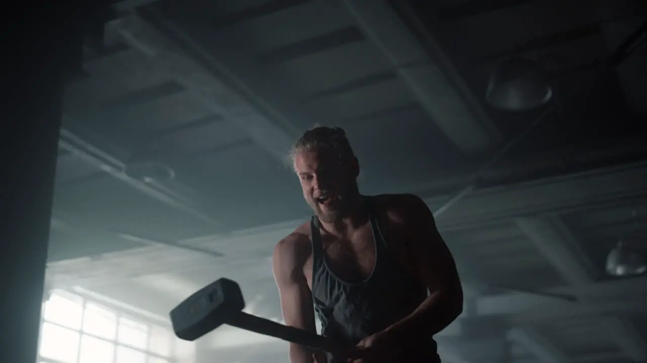 Man using hammer for strength exercise Fitness guy hitting rubber tire