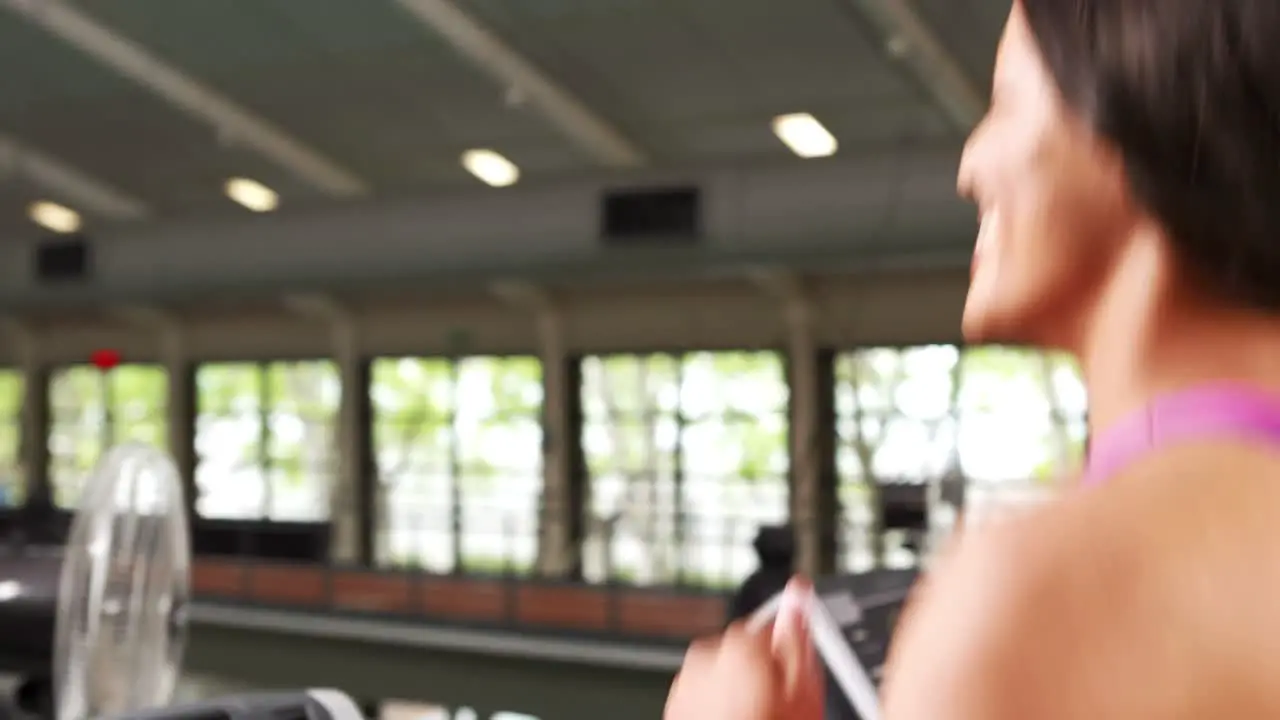 Fit woman running on treadmill with trainer timing her