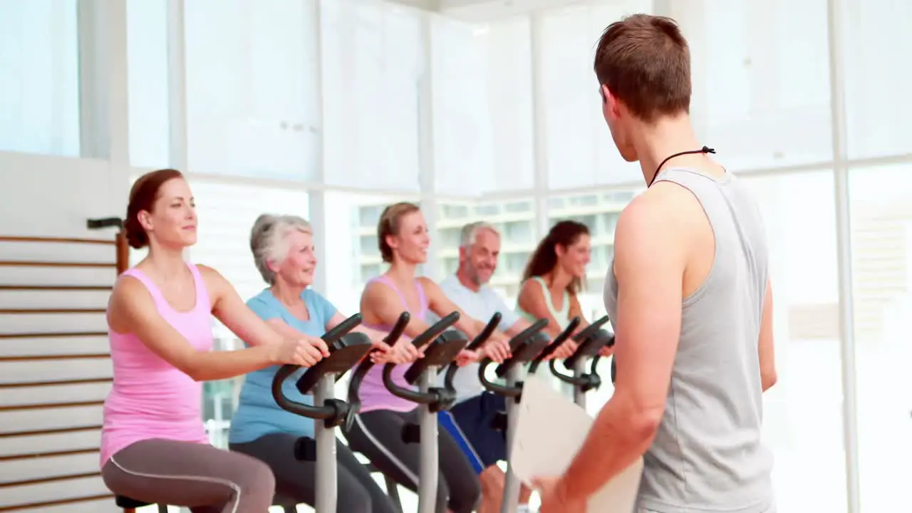 Spinning instructor smiling at camera in front of his class