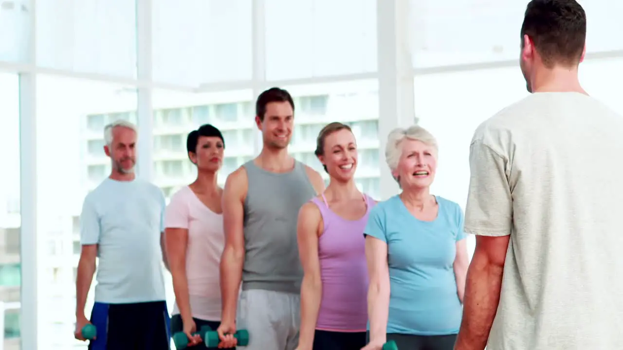 Fitness group lifting hand weights watching instructor