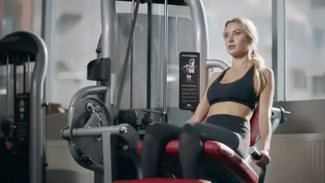 Sport woman making leg exercise on fitness machine in fitness gym