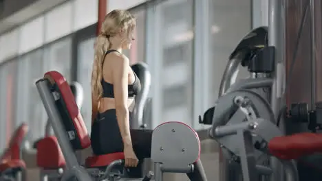 Fit woman doing fitness exercise on sport simulator in modern fitness gym