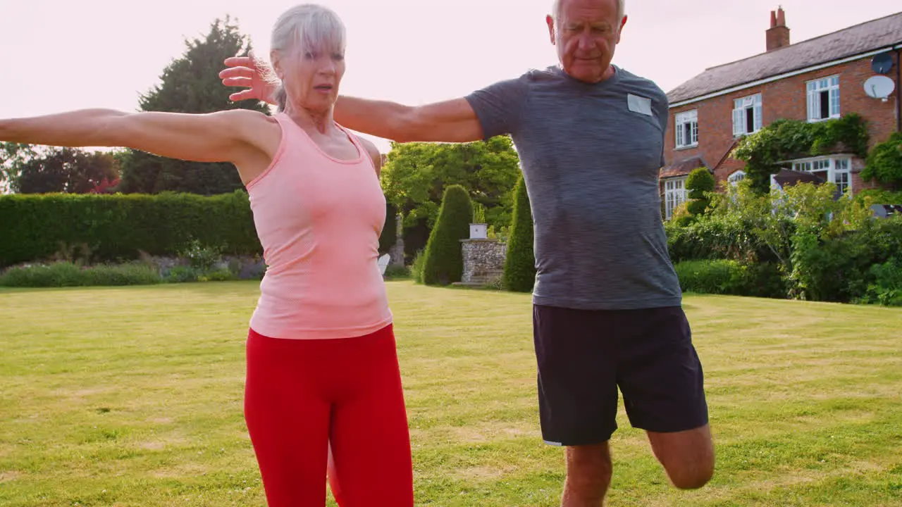 Healthy Senior Couple Exercising In Garden Together