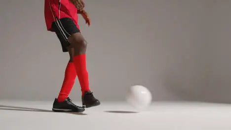 Close Up Of Male Footballer In Studio Kicking And Passing Ball