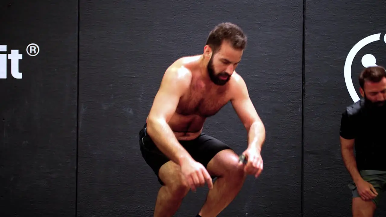 Shirtless muscular man jumping on top of the gym box while attempting a crossfit challenge