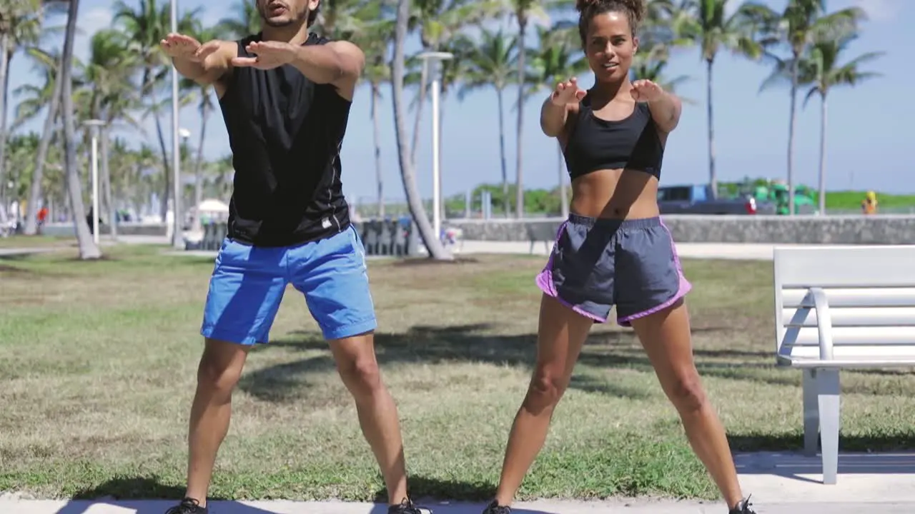 Athletic couple knee bending in sunny park