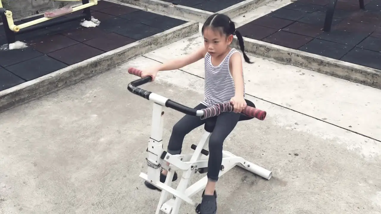 Asian child girl is exercising with a machine in public park in Bangkok Thailand