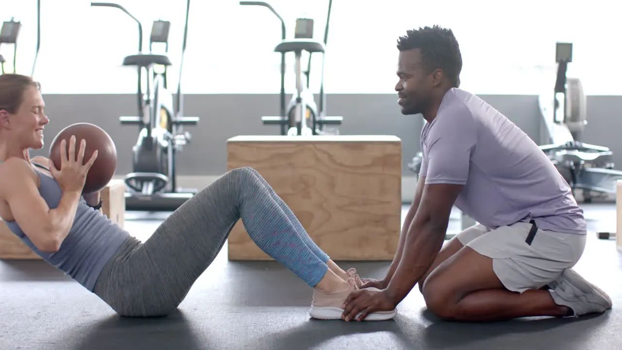 Fit young Caucasian woman and African American man exercise at the gym with a medicine ball