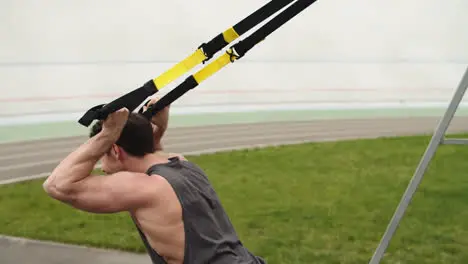 Fitness man exercising with trx suspension rope at stadium