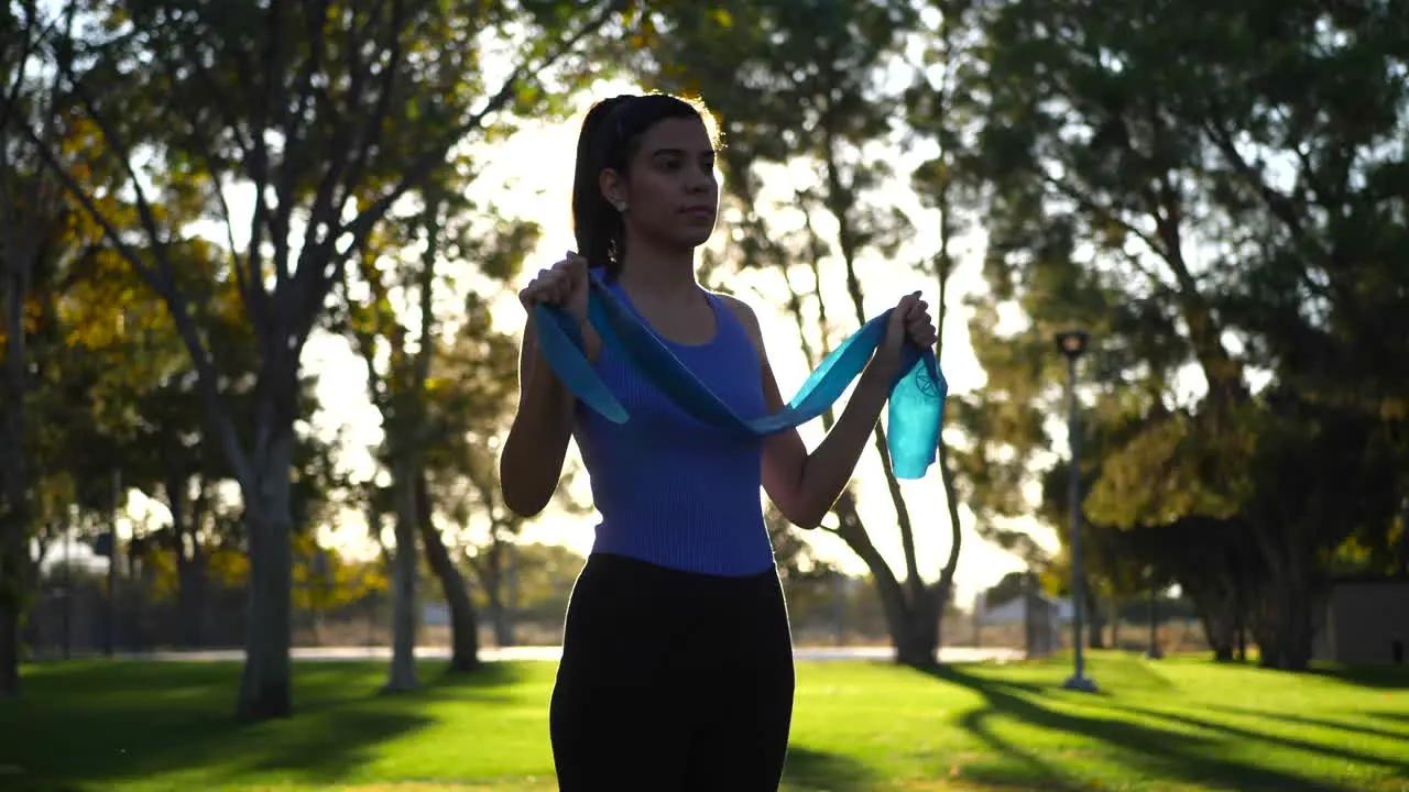 A beautiful young woman using resistance bands in her outdoor workout and exercise training at sunset SLOW MOTION