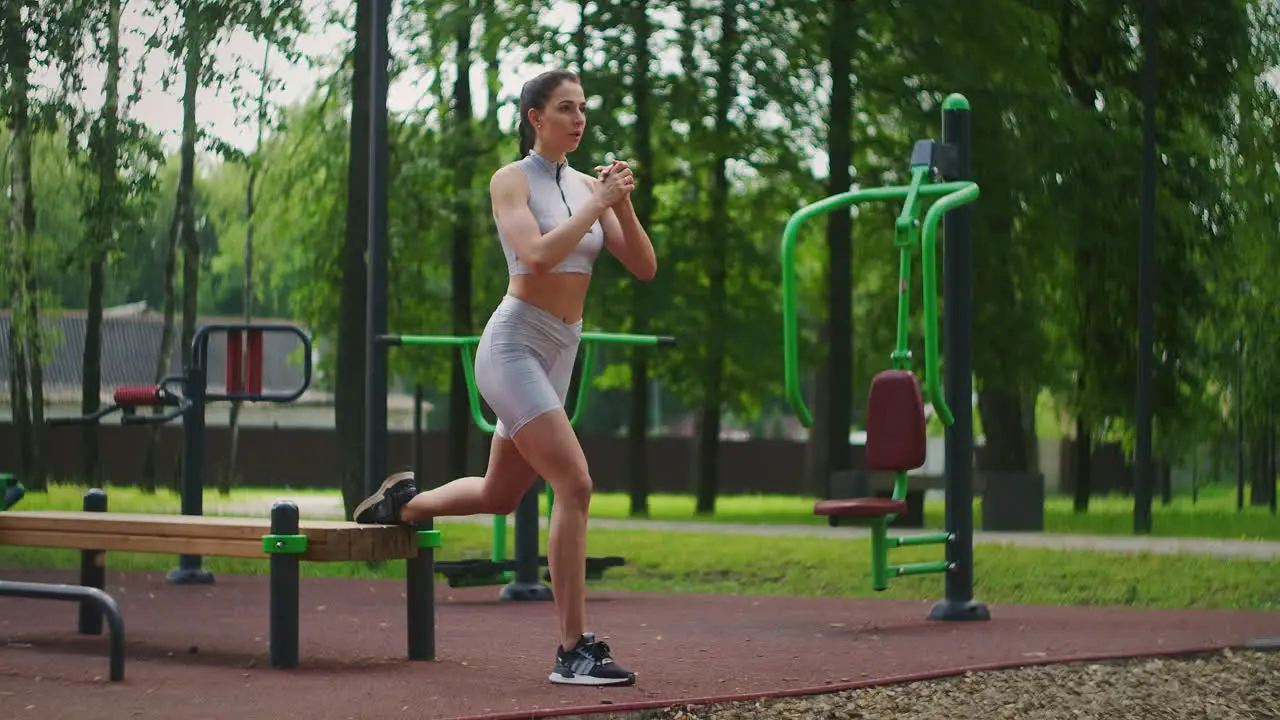 A young beautiful woman alone performs exercises in the Park in the summer on a bench Healthy lifestyle and sports training in the Park in summer