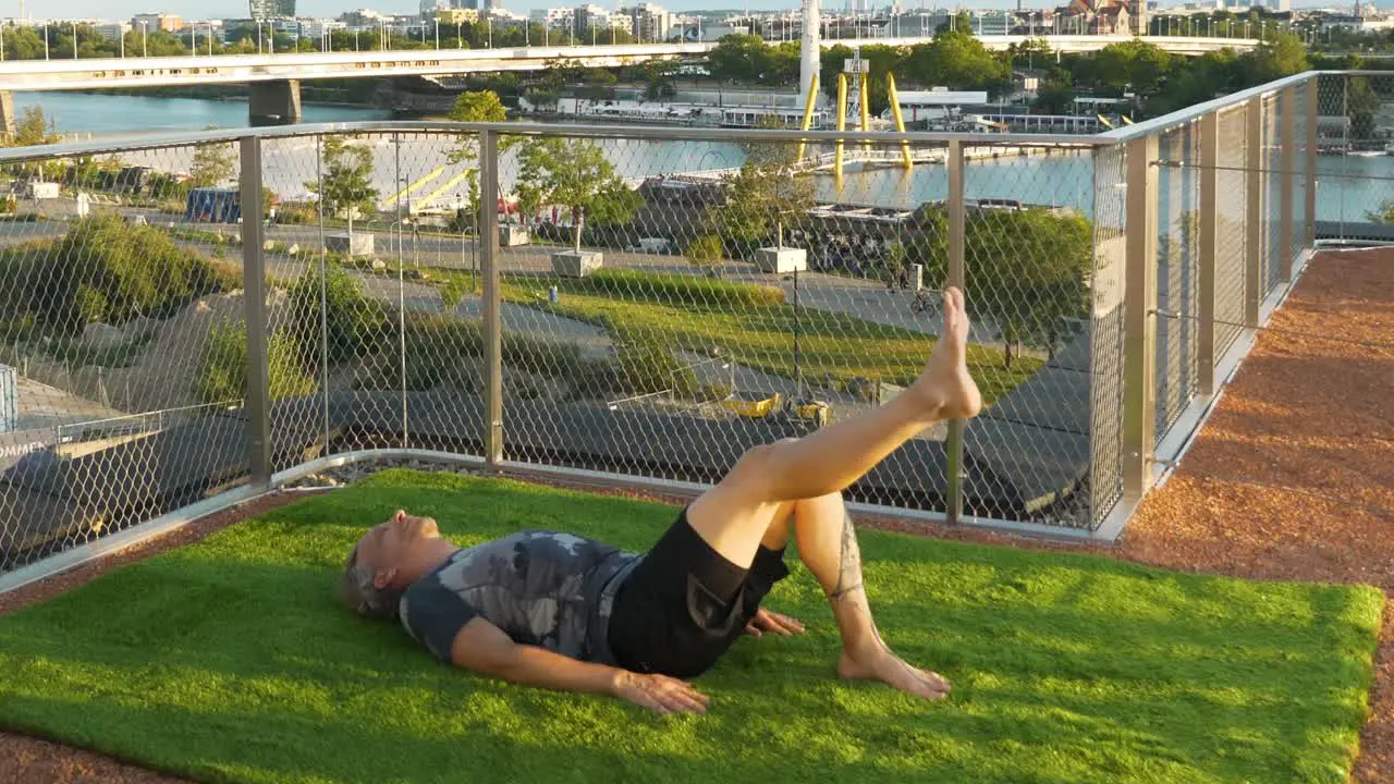 Man is doing Exercises on a modern terrace in Vienna with the beautiful Danube Island in the back 4K