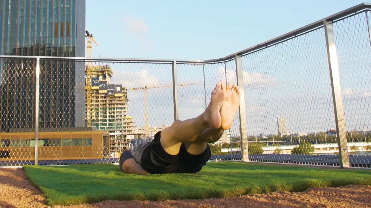 Tattoed Guy is doing Exercises on a terrace in front of a big Tower in Vienna during sunset 4K