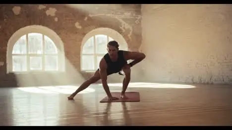 Male gymnast doing fitness in the solar hall Sports and gymnastics warm-up for muscle stretching and strengthening A guy in black sportswear goes in for sports in a sunny gym