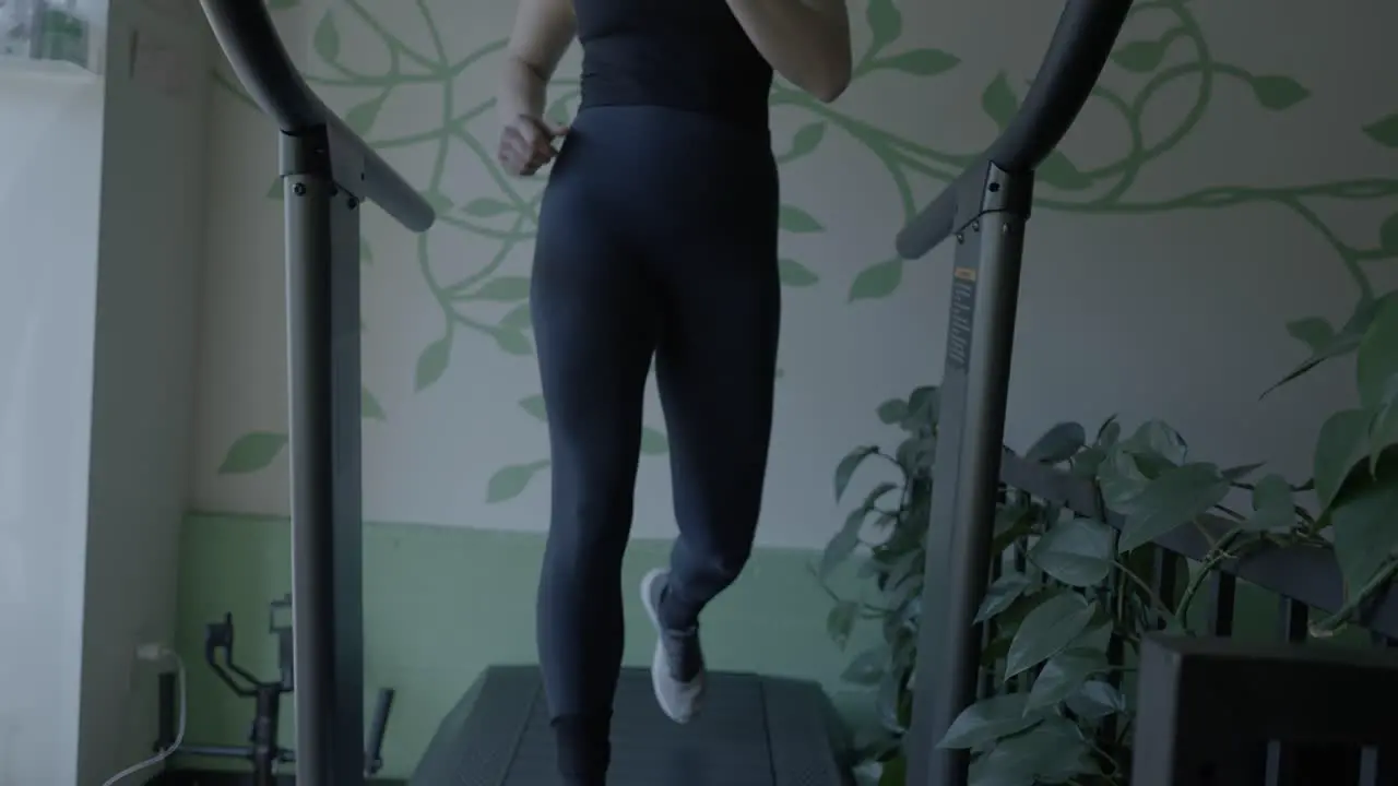 A rising shot of a white Female walking on a treadmill in a gym getting exercise