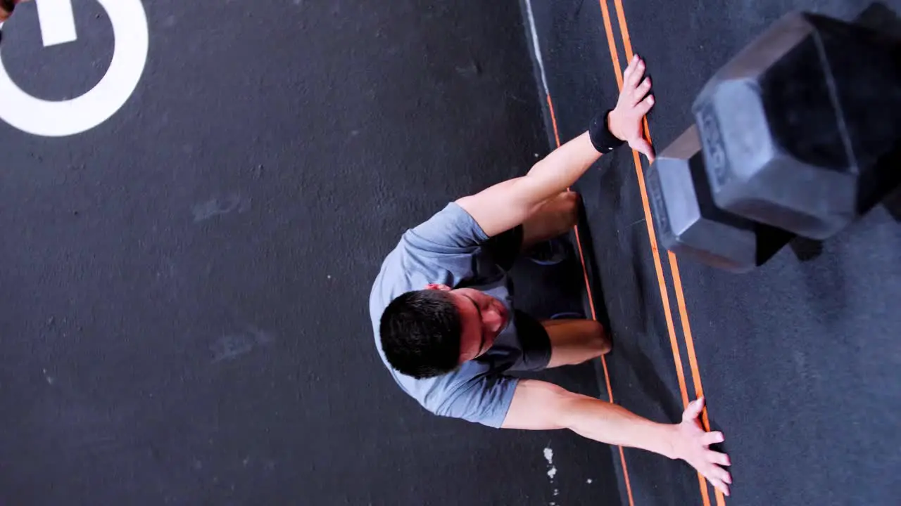 A shot of a young Caucasian man in the middle of a crossfit session in a gym performing a wall climb with his legs