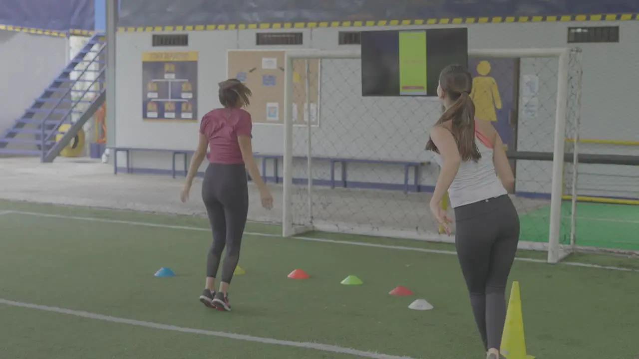 girls training on soccer field with jumping cones