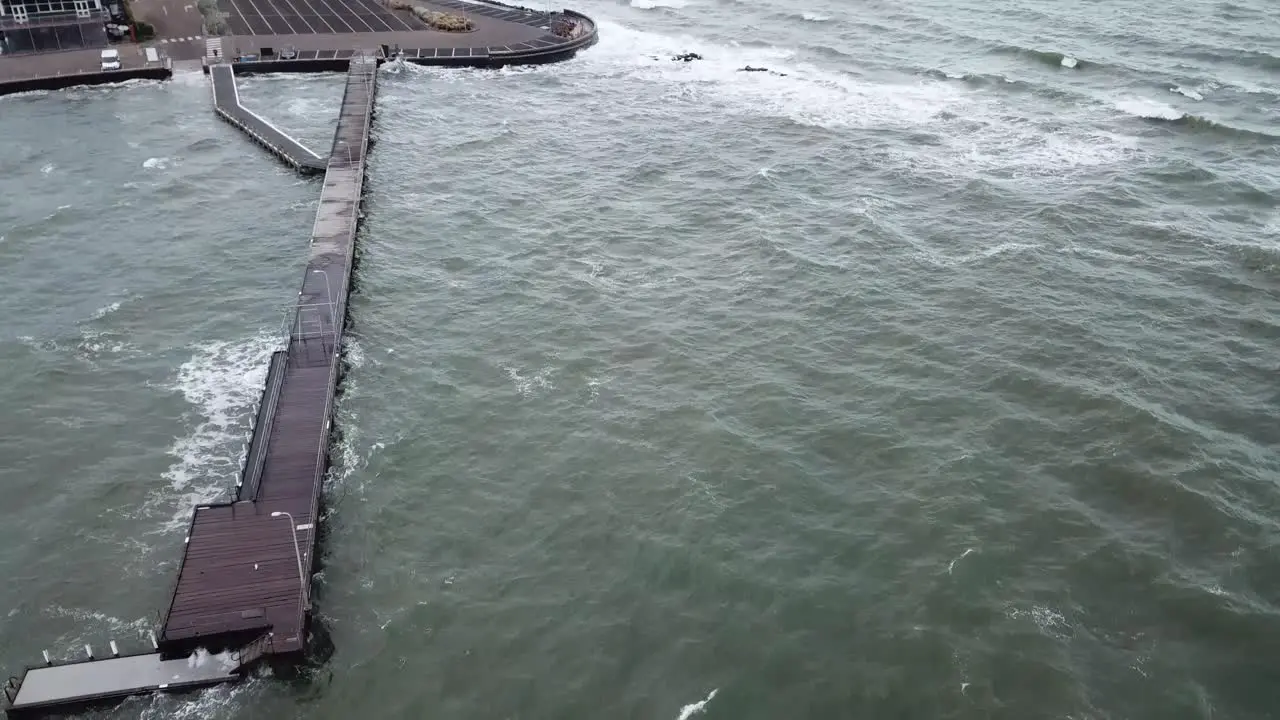 Drone aerial over ocean pier in Melbourne wavy windy cloudy day