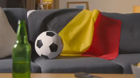 Flag Of Belgium Draped Over Sofa At Home With Football Ready For Match On TV 1