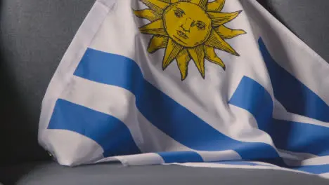 Close Up Of Flag Of Uruguay Draped Over Sofa At Home Ready For Match On TV