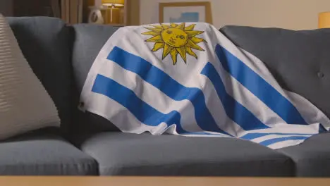 Flag Of Uruguay Draped Over Sofa At Home Ready For Match On TV