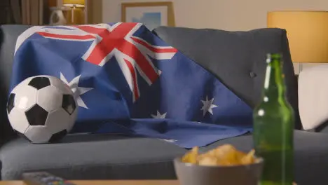 Flag Of Australia Draped Over Sofa At Home With Football Ready For Match On TV 3