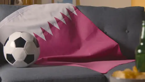 Flag Of Qatar Draped Over Sofa At Home With Football Ready For Match On TV 2