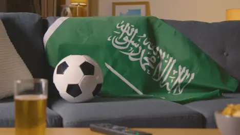 Flag Of Saudi Arabia Draped Over Sofa At Home Ready For Match On TV