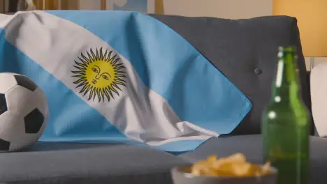 Flag Of Argentina Draped Over Sofa At Home With Football Ready For Match On TV 1