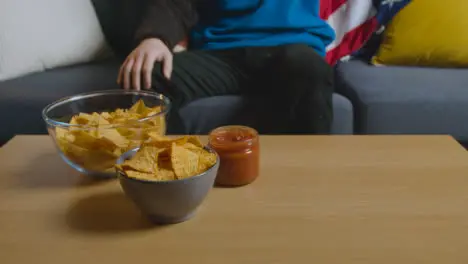 Person At Home Watching American Football Game On TV With Drinks Snacks And Ball 3