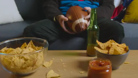 Person At Home Watching American Football Game On TV With Drinks Snacks And Ball 2